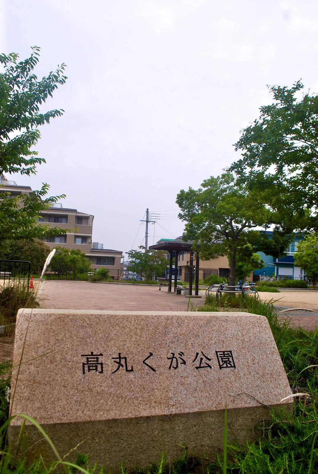 「高丸くが公園」と刻まれた石と、あずまやのある広場