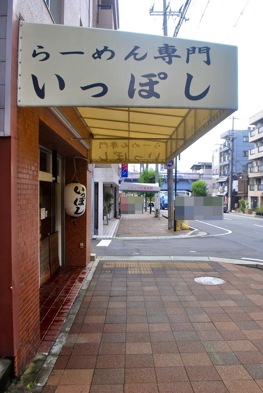 「らーめん専門 いっぽし」の日よけと提灯がある、角の店先